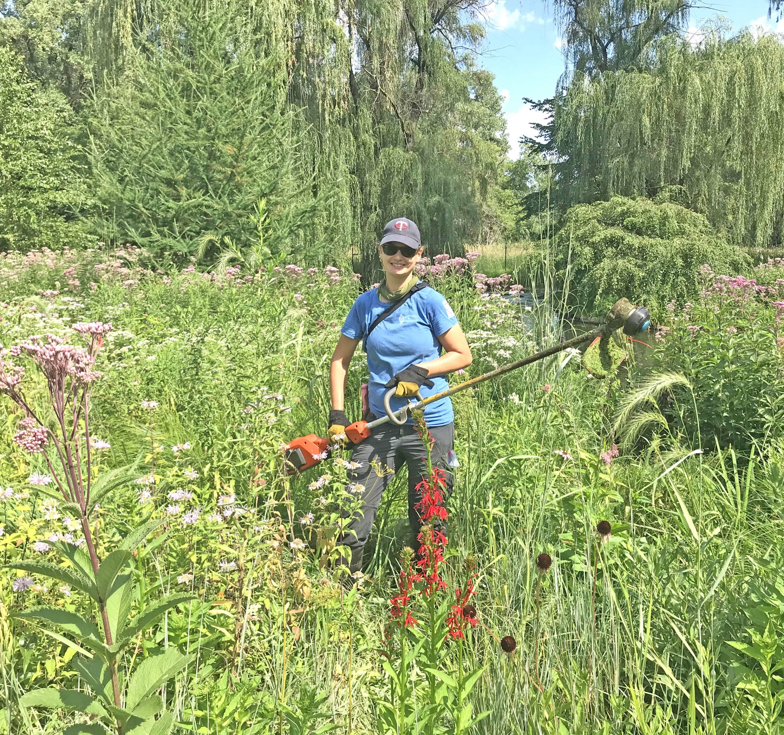 NST Staff holding weedwhip on herbicide-free natural landscape
